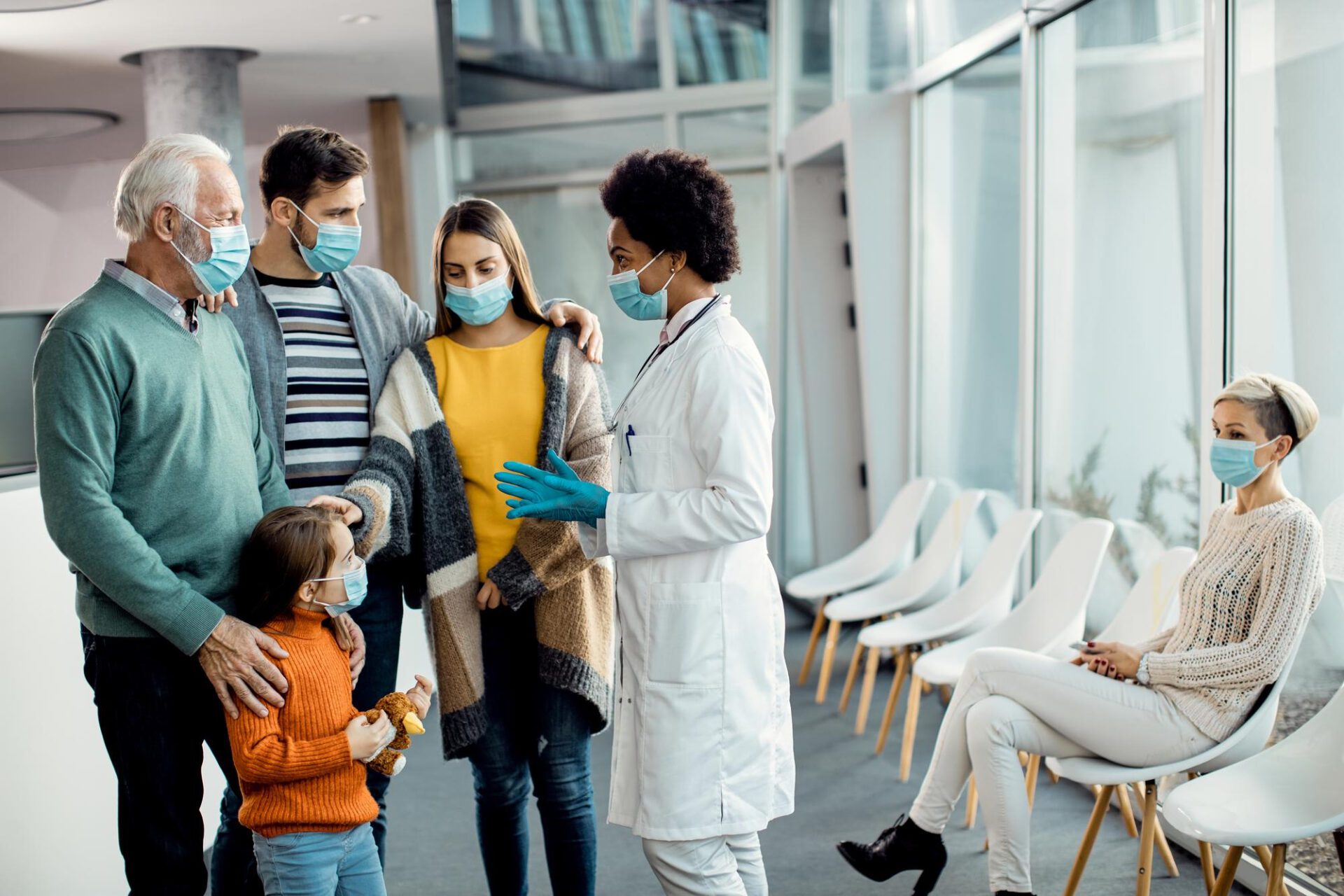 African american doctor talking to extended family at medical clinic during coronavirus pandemic