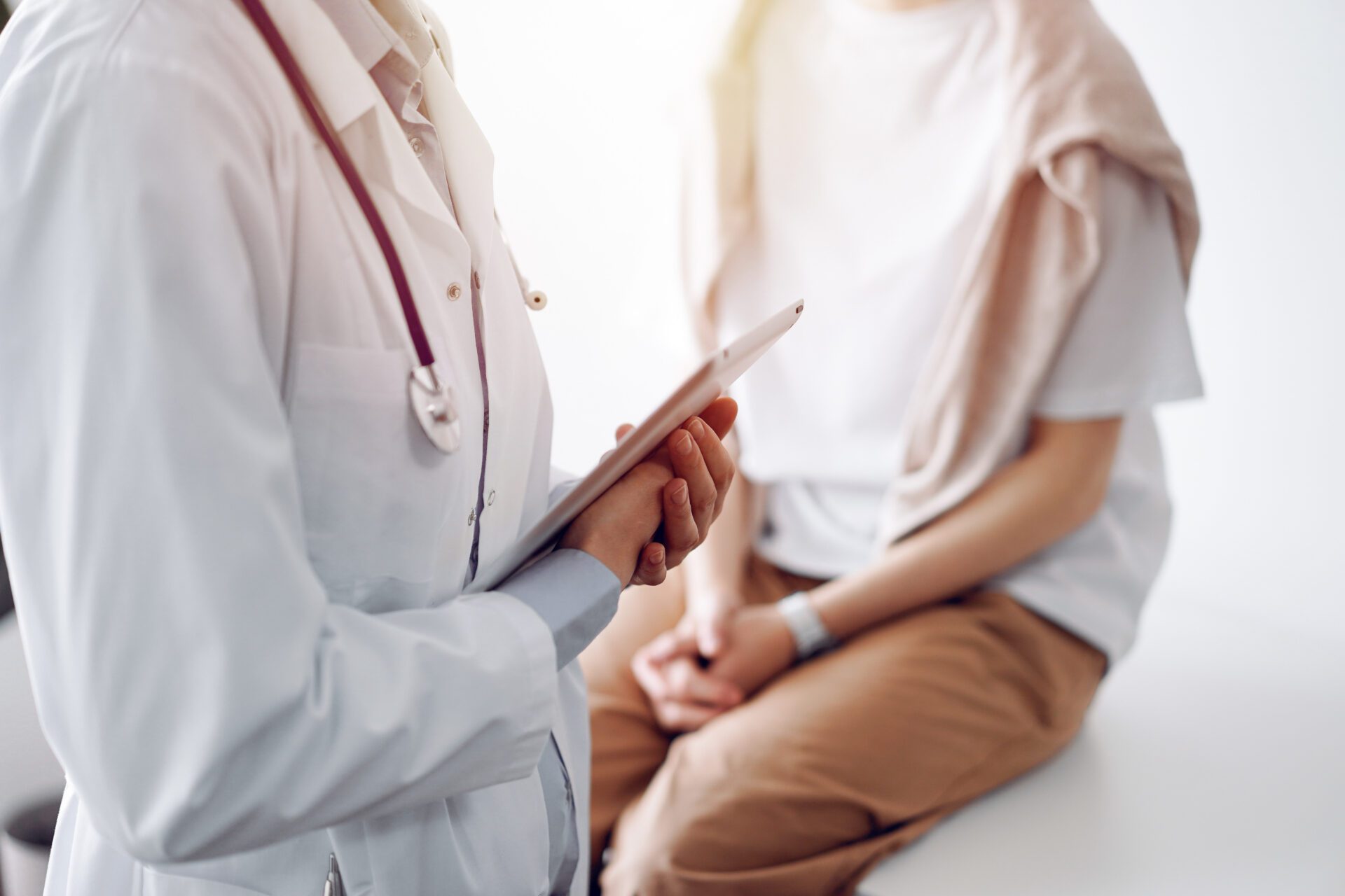 Doctor and patient discussing perfect health exam results. Friendly physician keeping tablet computer with her hands near a young woman. Medicine concept Festival of Trees event space